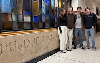 Four Exploratory Studies student senators standing in front of the stained glass display in the Purdue Union. 